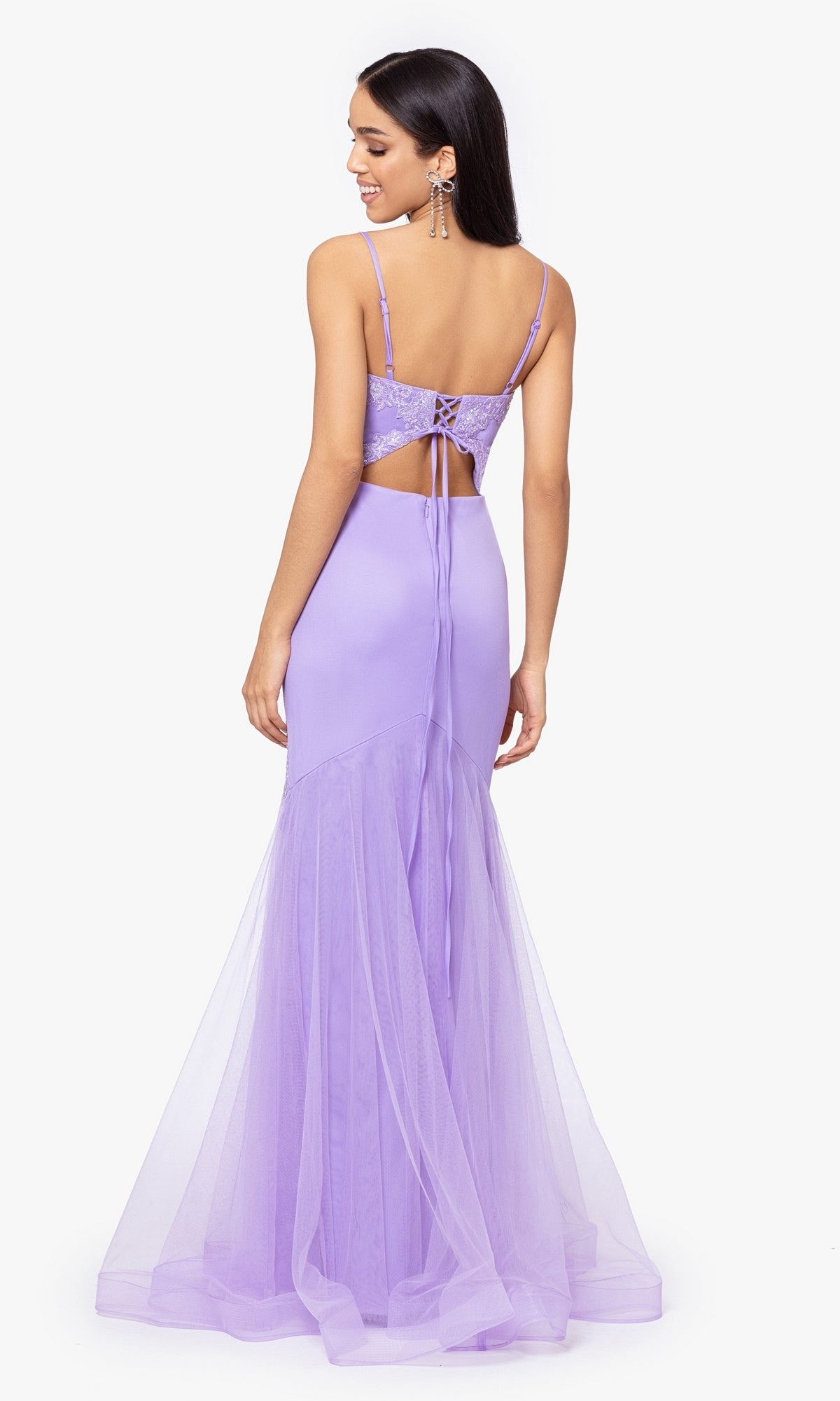 A woman smiles while facing away in the Blondie Nites Lilac Purple Long Prom Dress 4706BN, featuring a sleeveless, backless design with lace-up detailing and a tulle mermaid skirt.